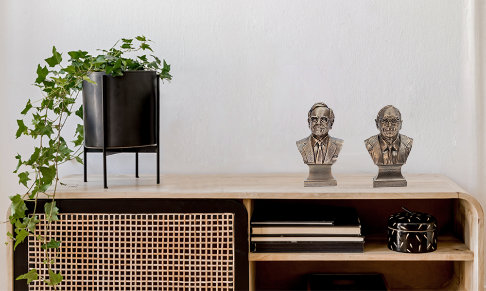 "Bronze Warren Buffett and Charlie Munger bust statues displayed on a modern Scandinavian-style sideboard, with a green plant placed beside them